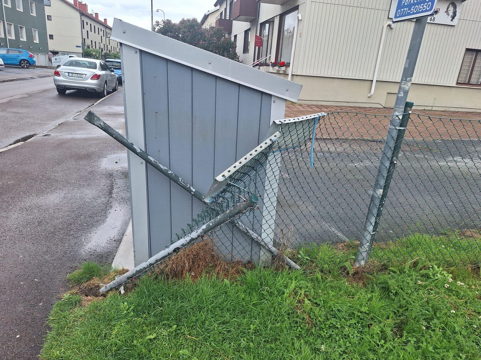 Samma staket före arbetet, nedkört med böjda stolpar och lossnad panel