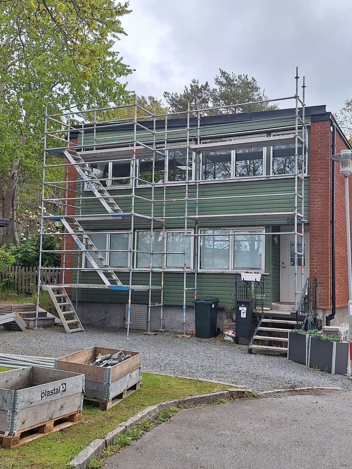 Samma villa med byggställning rest längs fasaden under målningsarbetet