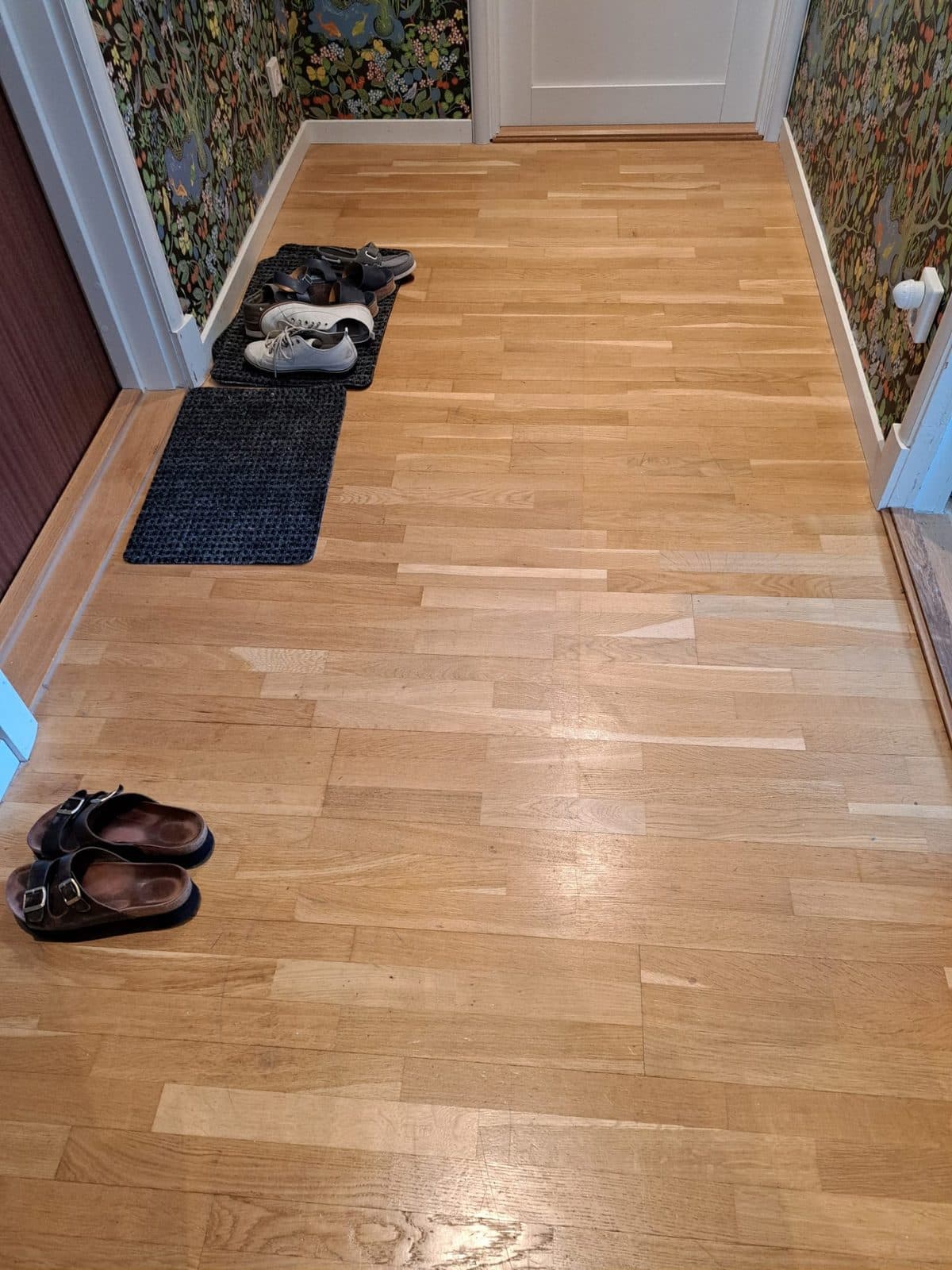 Samma hall före arbetet, med sliten och fläckig ekparkett på golvet
